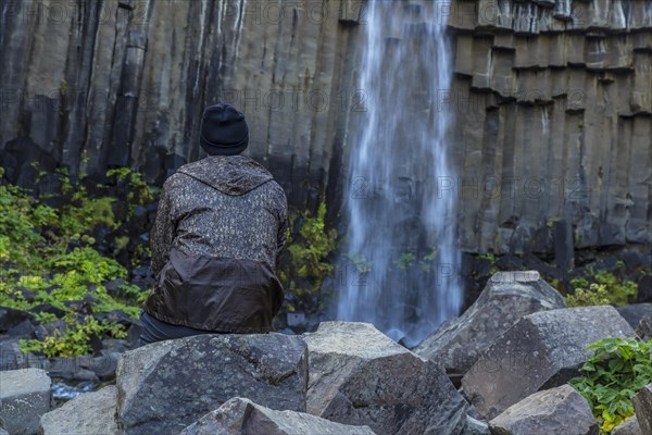 A man in Svartifoss waterfall