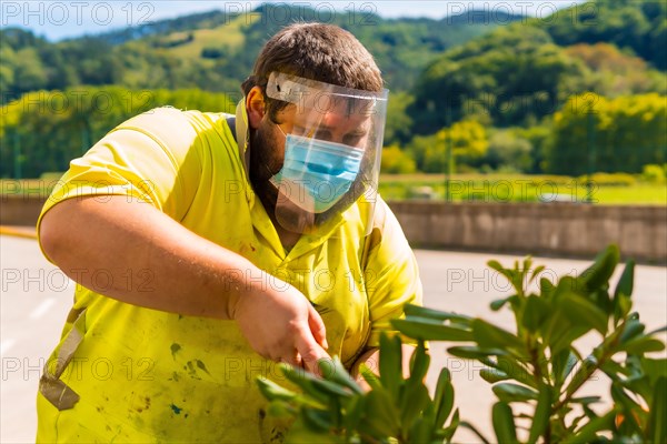 Worker in a recycling factory or clean point and garbage with a face mask and plastic protective screen