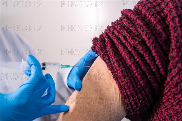 Female doctor injecting the coronavirus vaccine to an elderly lady. Antibodies