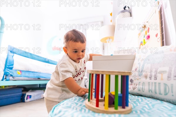 Young Caucasian mother playing with her in the room with toys. Baby less than a year learning the first lessons of her mother. Boy playing on the floor with toys