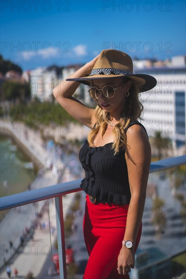 Portrait of a blonde woman spending her holidays in a luxury hotel on a terrace wearing a hat with sunglasses