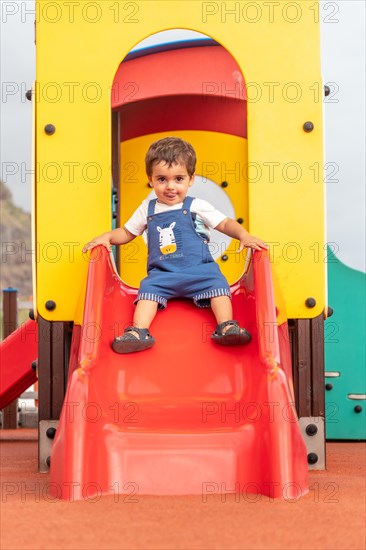 Baby playing in a playground having fun in summer