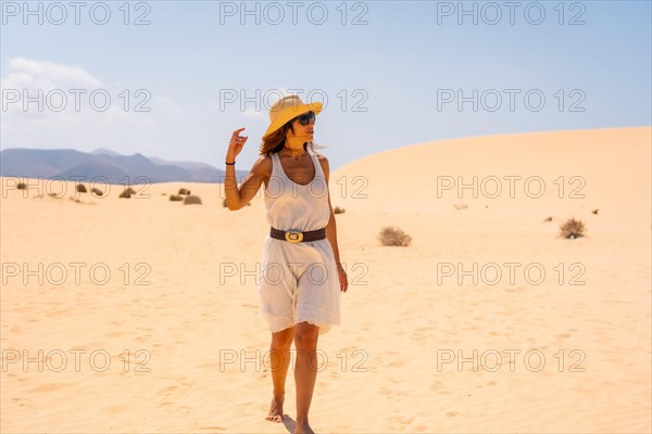 A young European tourist wearing a hat walking through the dunes of the Corralejo Natural Park