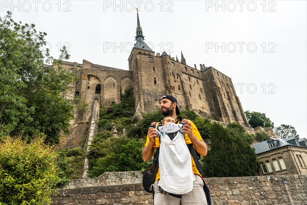 A young father visiting the famous Mont Saint-Michel Abbey in the Manche department