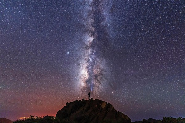 A young man with a flashlight below the beautiful milky way of the Caldera de Taburiente near the Roque de los Muchahos on the island of La Palma