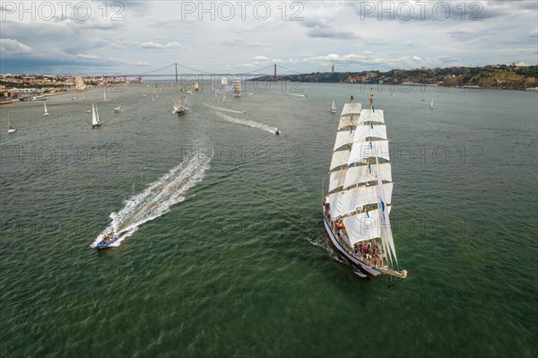 Aerial drone view of tall ships with sails sailing in Tagus river towards the Atlantic ocean in Lisbon