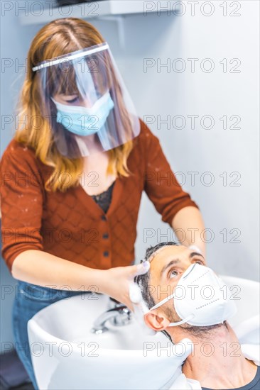 Hairdressers after the Coronavirus pandemic. Caucasian hairdresser with face mask and protective screen