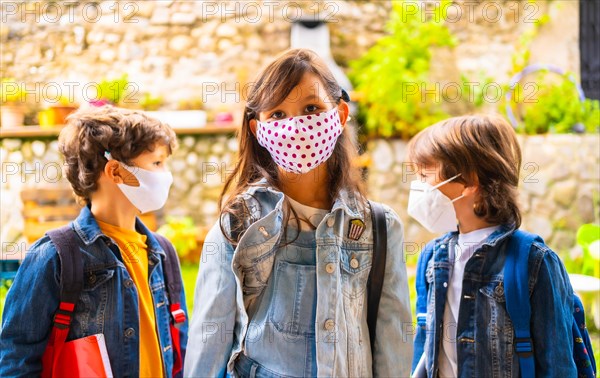 Three brother children with face masks ready for going back to school. New normality