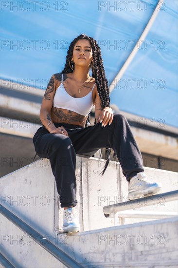 Young woman of black ethnicity with long braids and with tattoos