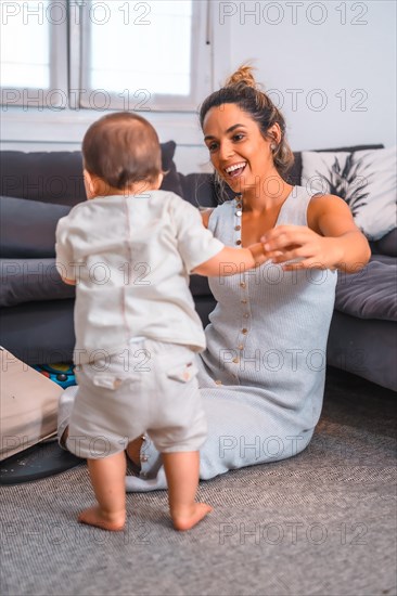 Young Caucasian mother with her son sitting on the floor next to the black sofa. Teleworking and caring for your child