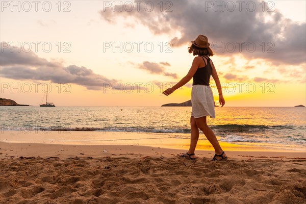Young woman walking at sunset in Cala Comte beach on the island of Ibiza. Balearic