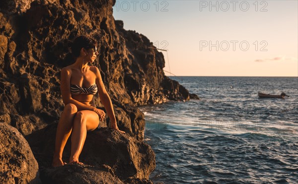 A young woman looking at the sea at sunset in the town of Poris de Candelaria on the nort-west coast of the island of La Palma