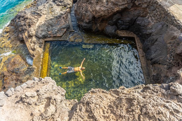 A young man enjoying a natural sea pool in the cove of Puerto de Puntagorda