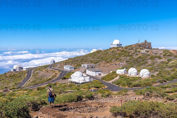 A young man on the trail looking at the telescopes of the Roque de los Muchachos national park on top of the Caldera de Taburiente