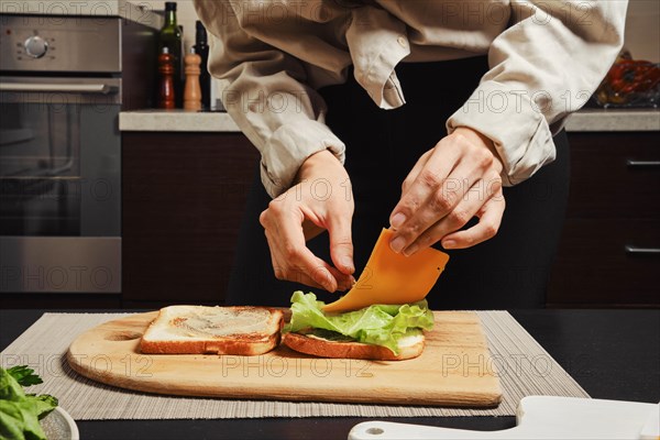 Unrecognizable woman makes sandwich with cheddar cheese