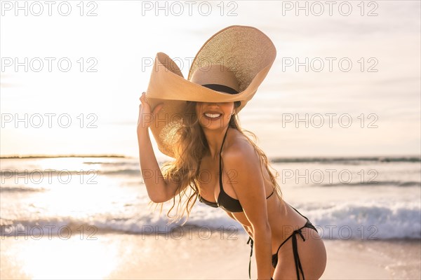 Portrait of a beauty and sensual woman in bikini and sun hat on the beach