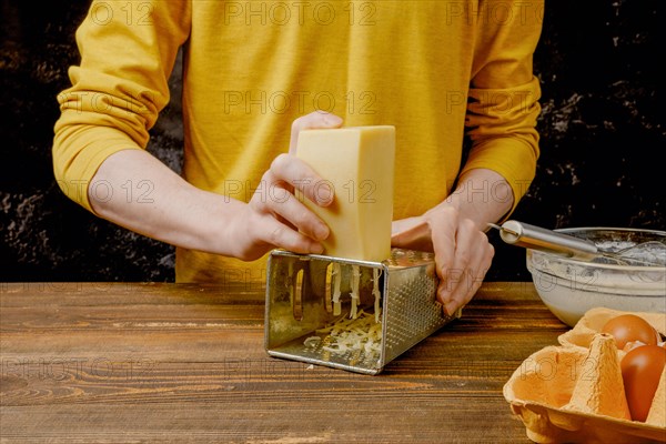 Close up of male hands grating cheese on kitchen table