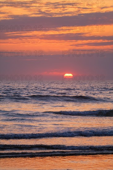 Ocean waves on sunset with setting sun background