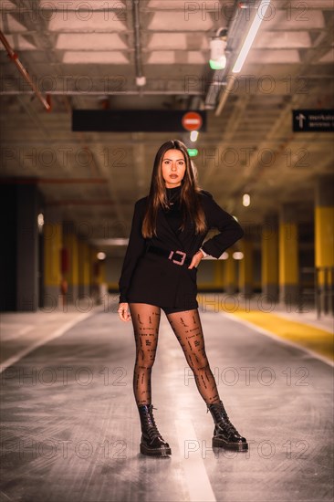 Young caucasian model with black jacket posing in an empty underground car park. Night urban session in the city