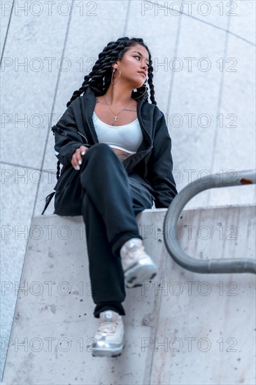 Urban session. Young woman of black ethnicity with long braids and with tattoos