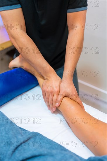 Physiotherapeutic massage to an unrecognizable woman lying on a stretcher on her leg