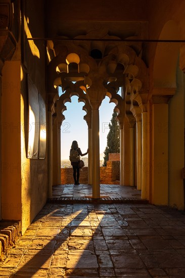 A young woman at sunset from the Arab doors of a courtyard of the Alcazaba in the city of Malaga