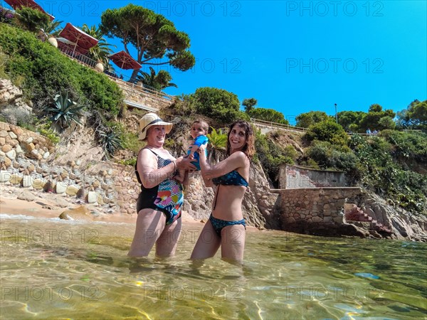 A family with their baby enjoying the summer in Cala Canyet next to the town of Tossa de Mar. Girona