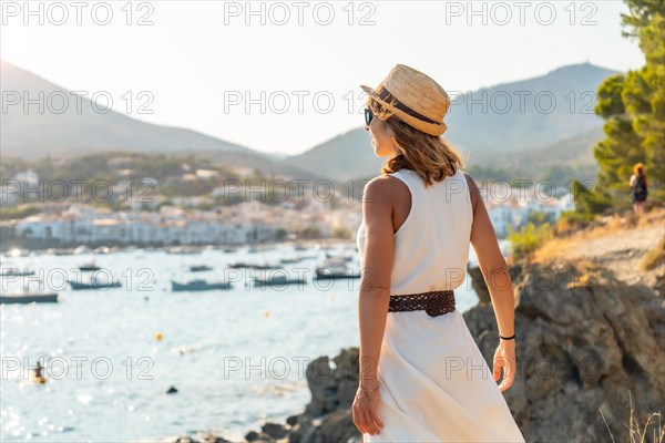 A young woman in a white dress and hat in Cadaques enjoying the summer