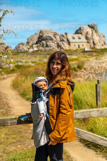 A young girl with her baby visiting the house among rocks by the sea