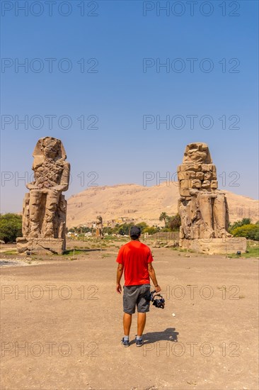 A young photographer visiting two Egyptian sculptures in the city of Luxor along the Nile. Egypt