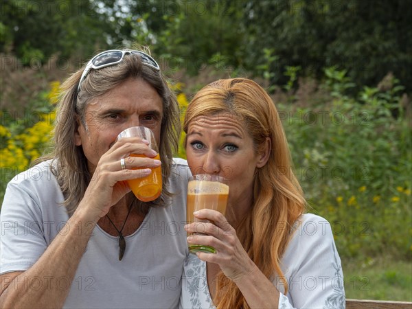 Man and woman in the garden with freshly squeezed fruit juice