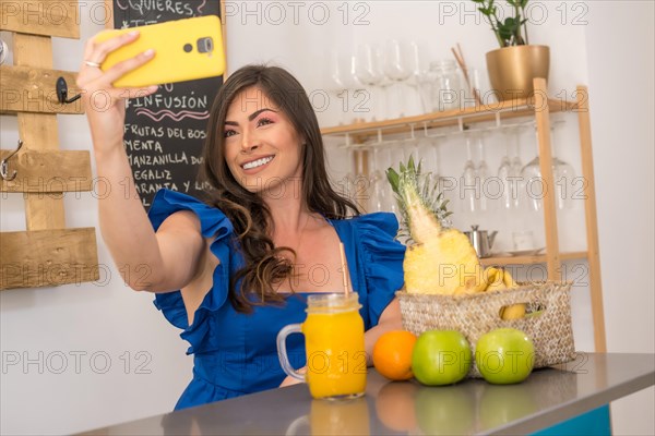 Smiling woman taking a selfie in a cafeteria counter with healthy fruit and juices