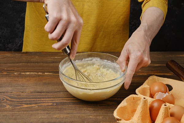 Close up view of man whisking eggs and flour in a glass bowl