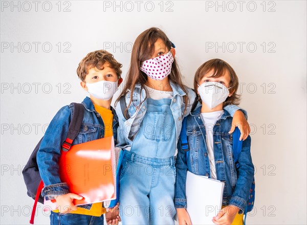 Three children with face masks ready to go back to school. New normality