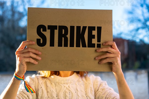 A female activist holding a sign with the slogan of the hollywood actors and writers strike with the blue sky in the background