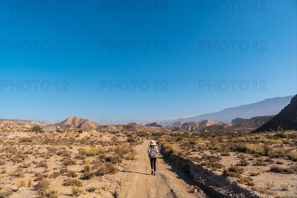 A young hiker girl with a hat visiting the landscapes of Colas de Dragon in the desert of Tabernas