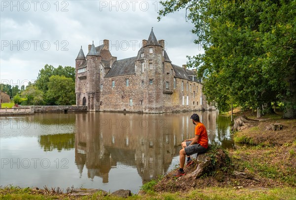 A young man at the lakeside medieval Chateau Trecesson