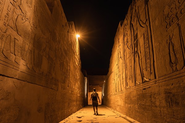 Un joven turista en los pasillos a la noche del templo de Kom Ombo con el traje tradicional