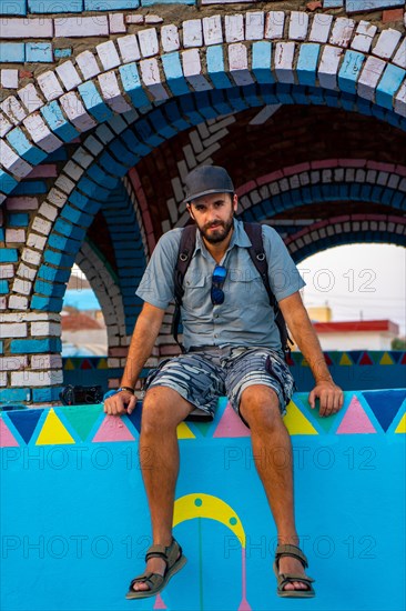 A young tourist sitting on a beautiful terrace of a traditional blue house in a Nubian village along the Nile river and near the city of Aswan. Egypt