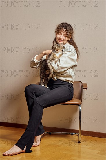 Barefoot woman hugging and petting her tabby cat