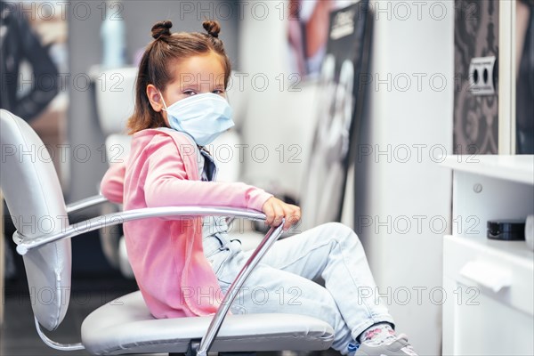 Girl sitting on the chair with pigtails finished. Reopening with security measures for hairdressers in the Covid-19 pandemic