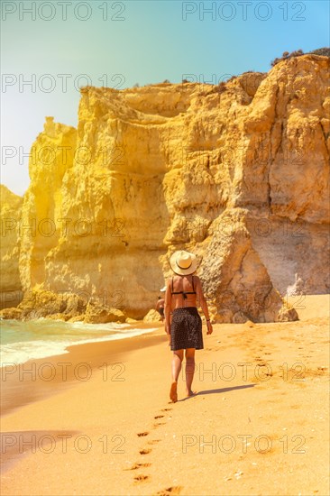 A woman with a hat at sunset on the beach at Praia da Coelha