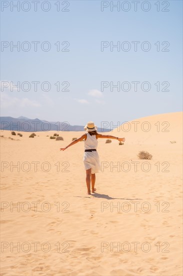 A young tourist wearing a hat walking through the dunes of the Corralejo Natural Park