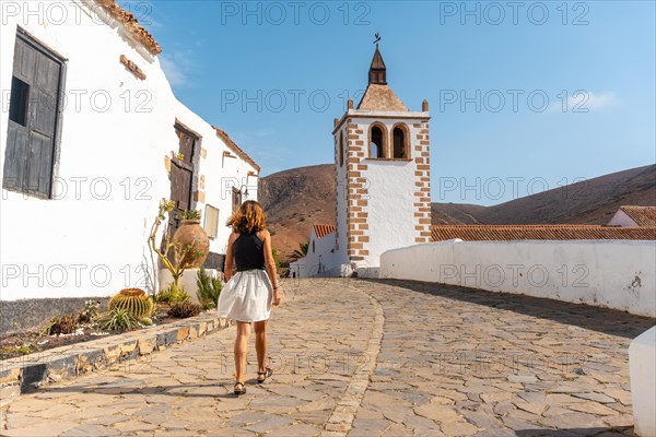 A young tourist girl walking next to the white church of Betancuria