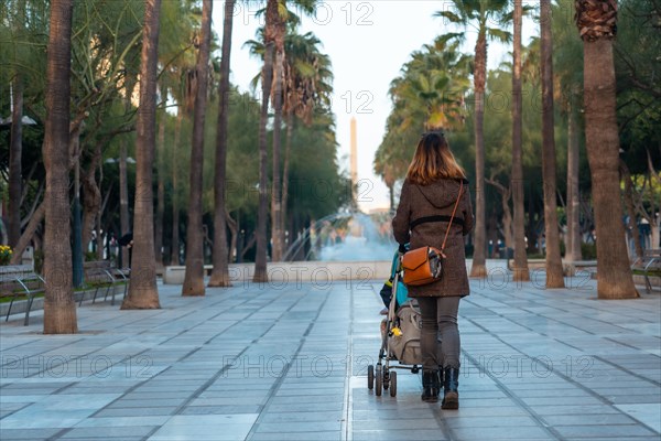 A young woman walking next to the palm trees in the Belen street of the Rambla de Almeria