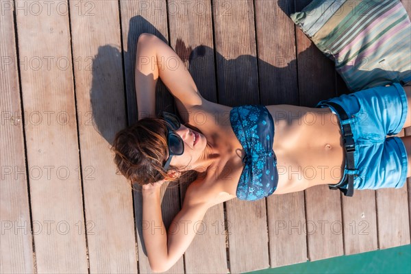 A young woman lying enjoying the holidays on the wooden walkway on the Isla de Lobos
