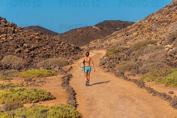 A young woman with a blue bikini on the trail to the north of the Isla de Lobos