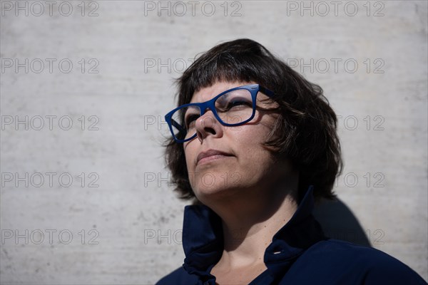 Headshot on a Elegant Woman with Eyeglasses and Leaning on a Concrete Wall in a Sunny Day in Switzerland