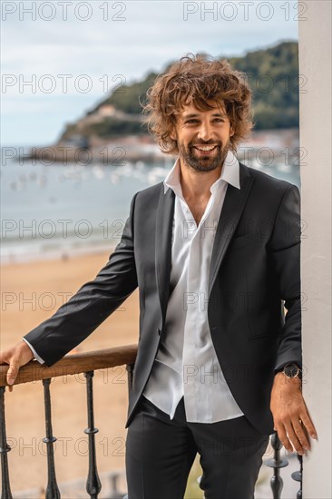 Street style with a young brunette caucasian man in a black suit and a white shirt in a luxurious hotel