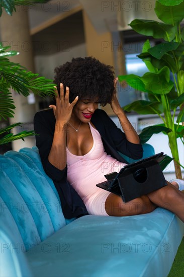 Young entrepreneur of black race and afro hair making a video call with great joy and amazement